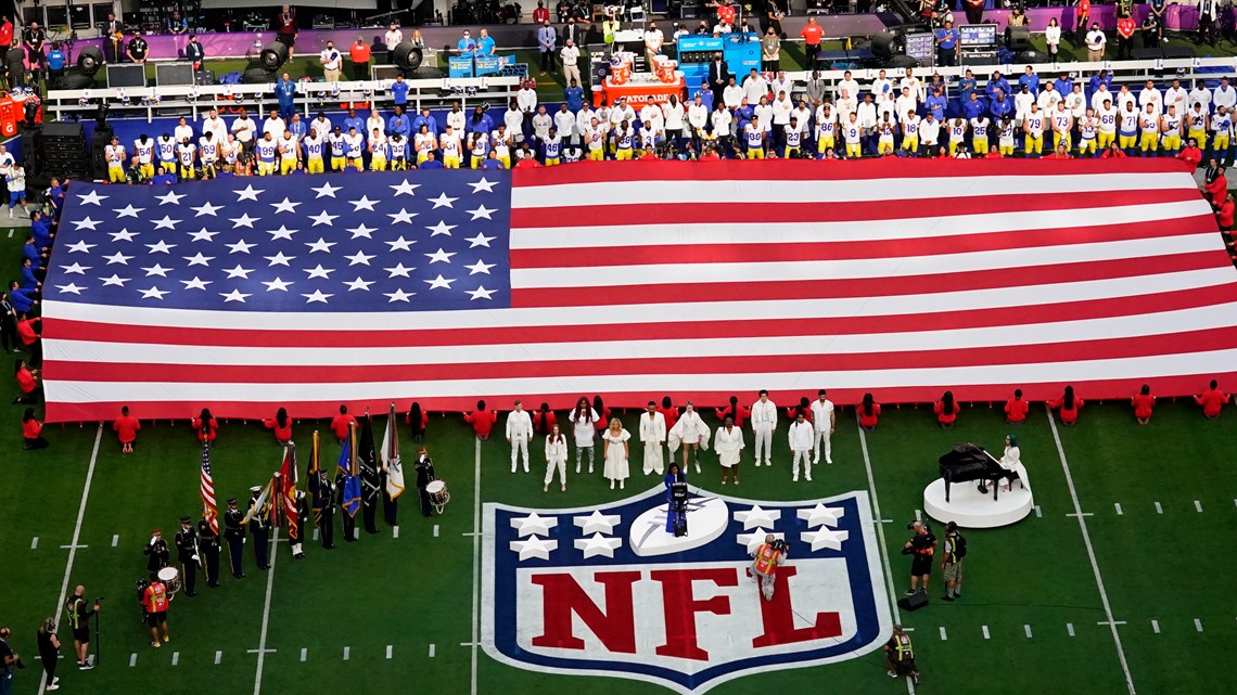 An American flag is stretched across the field at SoFi Stadium during the  national anthem before the NFL Super Bowl 56 football game between the Los  Angeles Rams and the Cincinnati Bengals