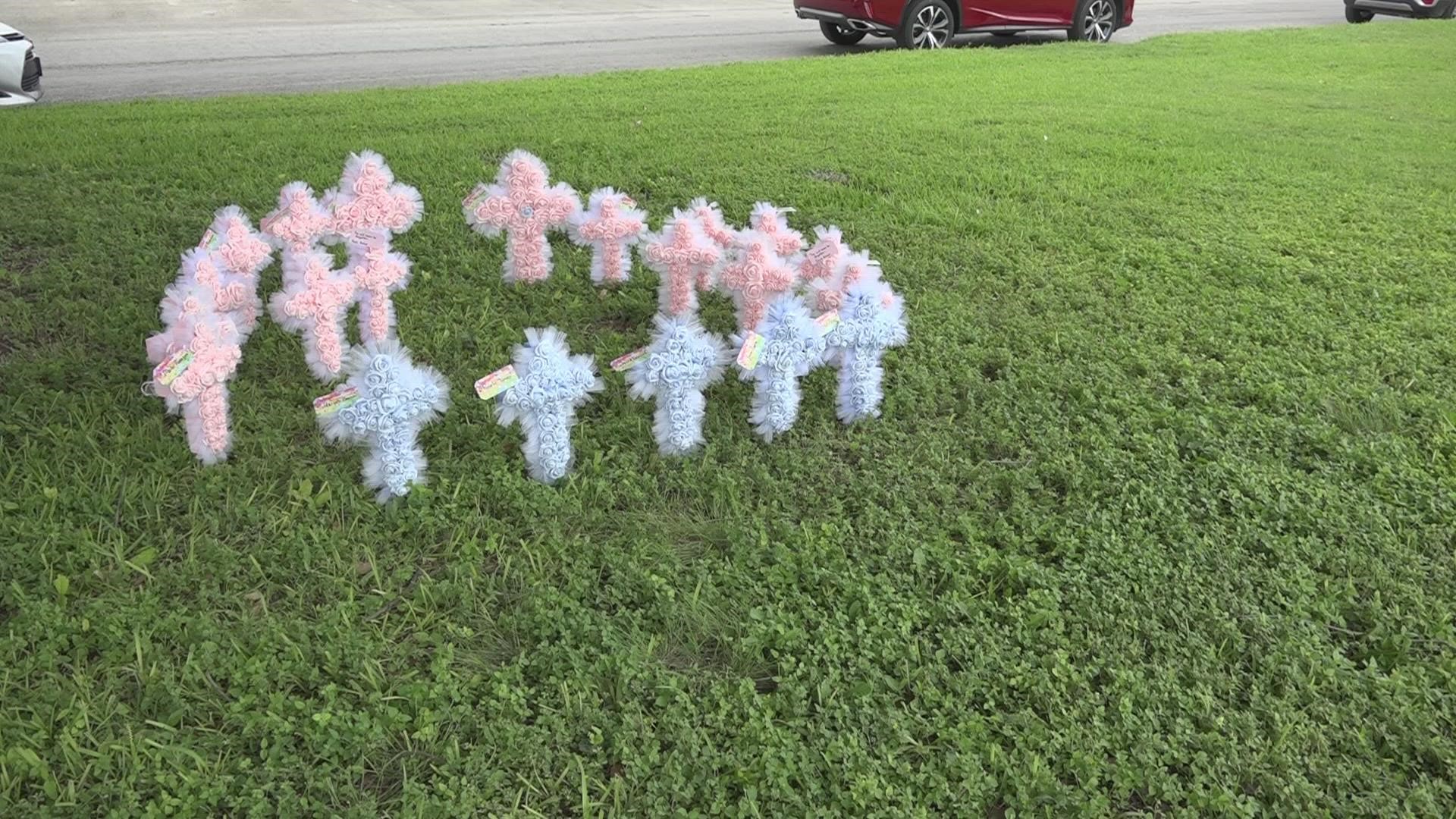 Each cross is decorated with roses and has a card with a note and the name of each victim.