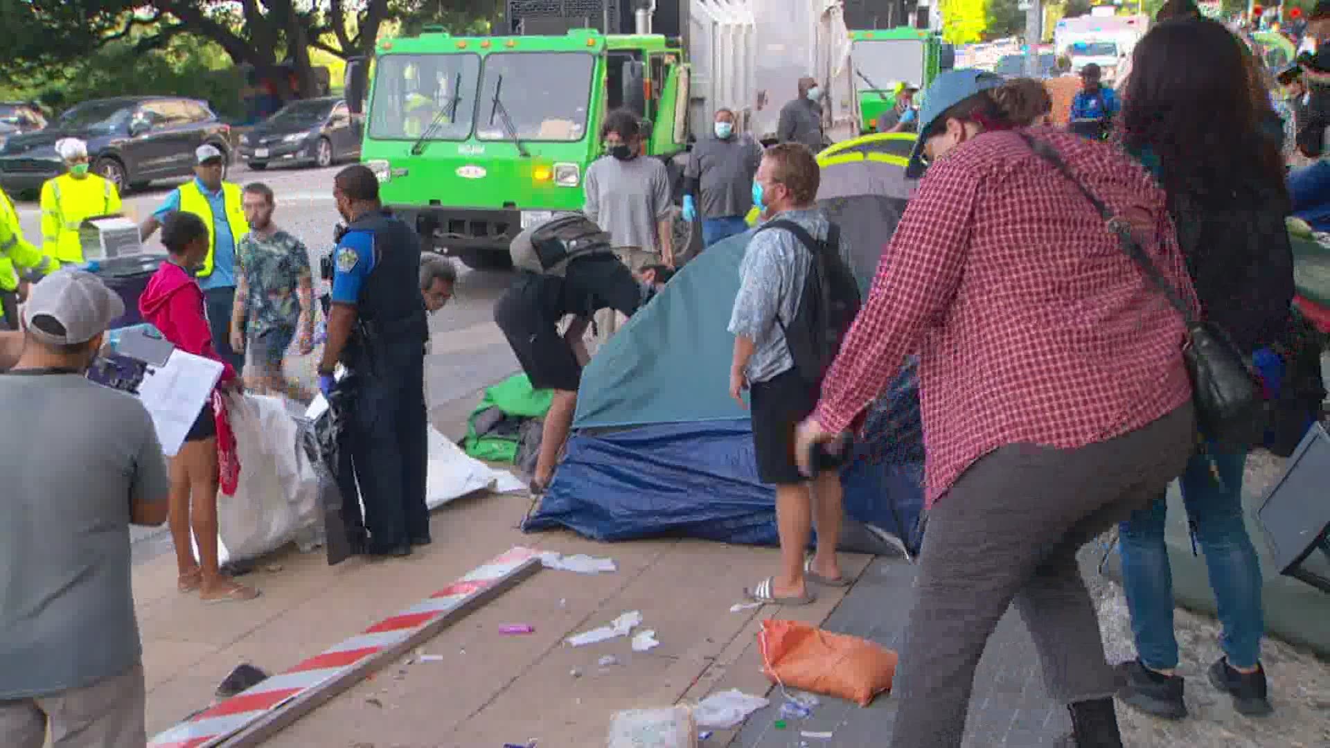 People clashed with crews cleaning up homeless tents outside Austin City Hall Monday.