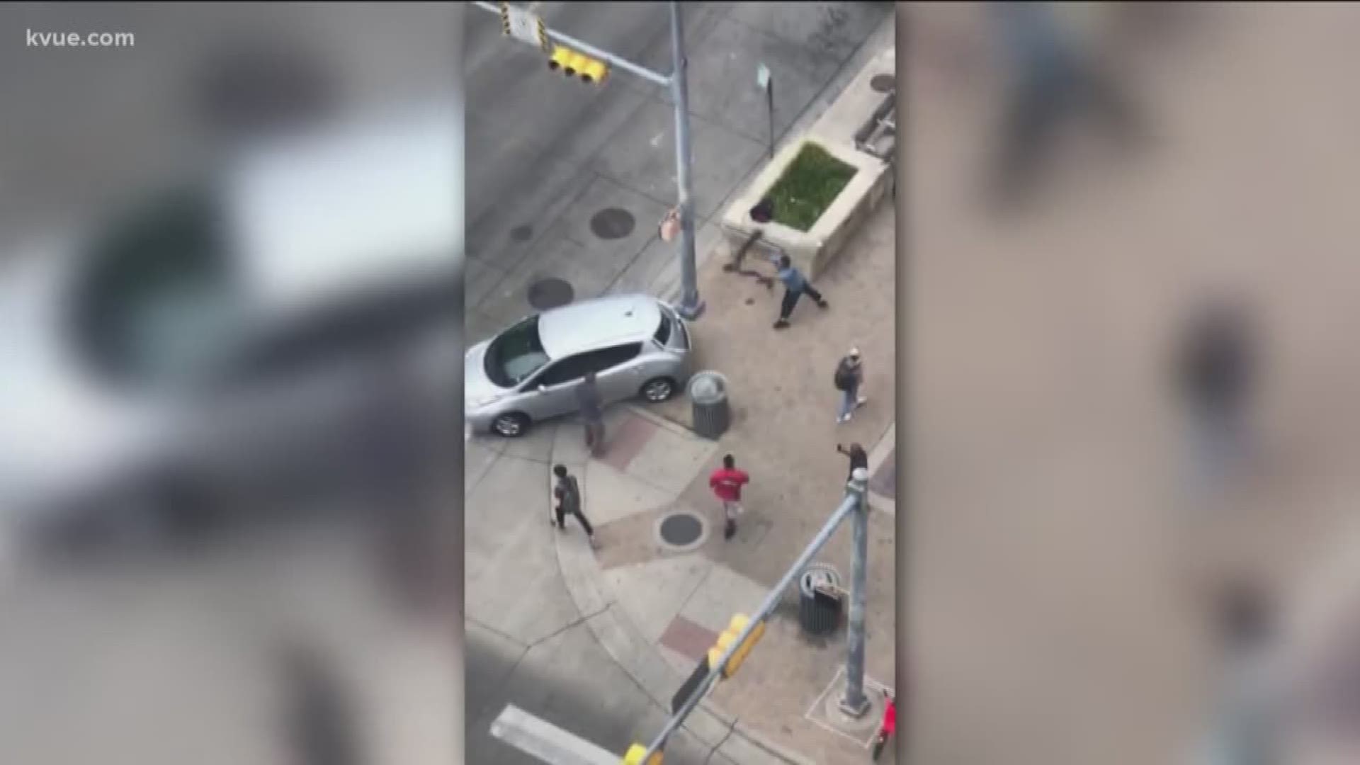 The video shows two men fighting in Downtown Austin before one of them throws a scooter through the back of a car window.